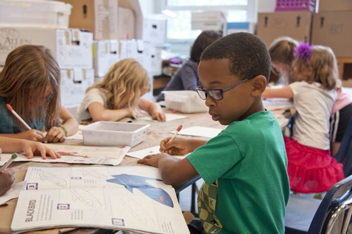 Group of young children at a table drawing and painting.